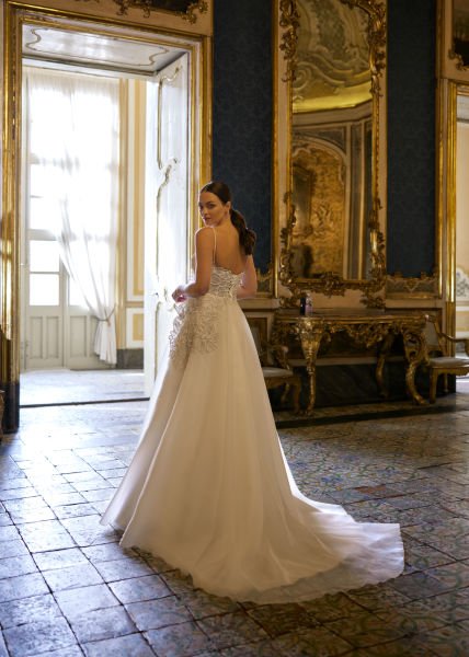 Hellenic style wedding dress model with thin spaghetti straps, decorated with 3D flowers, and skirts made of organza fabric